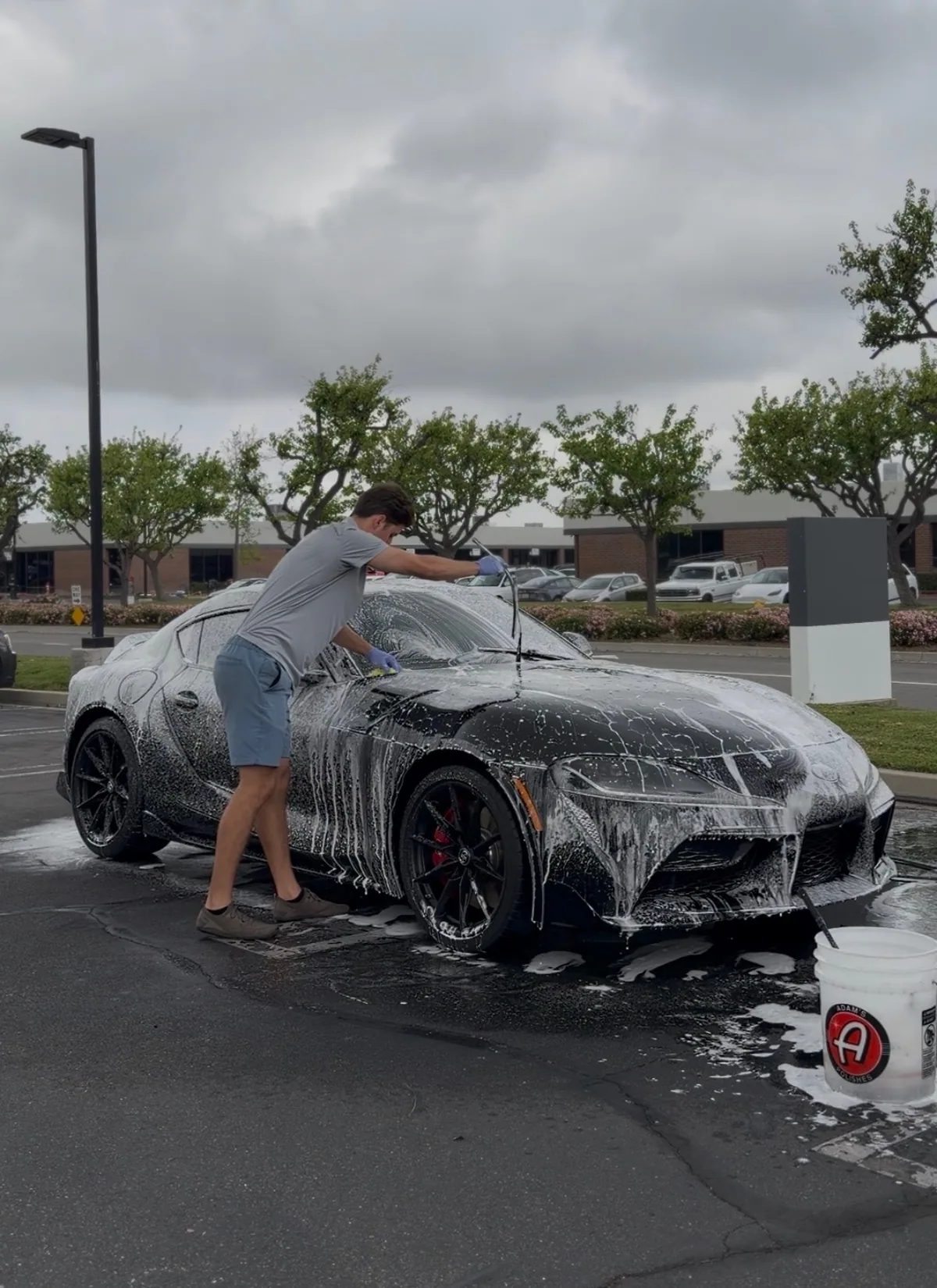 Hand-washing a black Toyota Supra, working carefully across the soapy paintwork